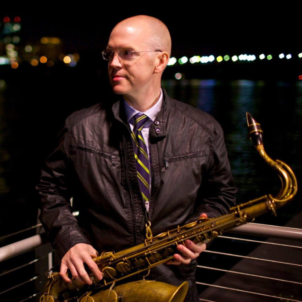 Tedd Baker holding his saxophone while on stage